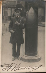 A man in a naval uniform standing beside a large shell. World War I Postcard Postcard Postcard