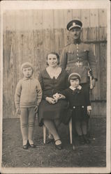 A man in a military uniform poses with his family World War I Postcard Postcard Postcard