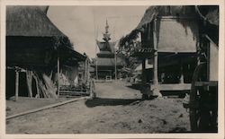 A temple is shown near thatched-hut structures in Sumatra Postcard