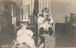 Two young kids sitting and playing in a living room. Postcard