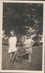 Girl and Boy Dressed in White Next to Wagon Postcard