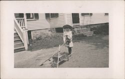 Little Girl in White Dress Pushing Wheelbarrow Postcard