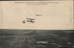 Two very early aeroplanes fly above a field Postcard