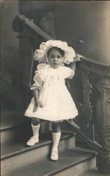 Child in Frilly White Hat on Stiars Postcard