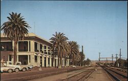 Needles Rail Road Depot, Palm Trees, Trucks, CA Postcard