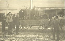 Men standing in a wagon in front of the dry goods store Postcard Postcard