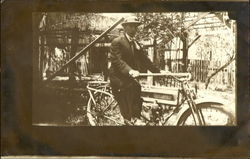 Man riding an early motorcycle Postcard