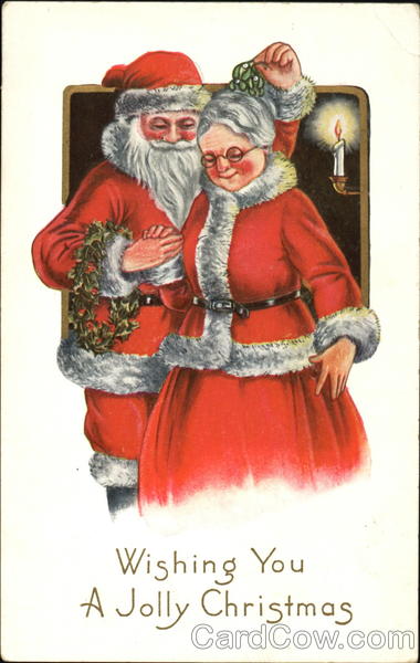 Santa holds mistletoe over Mrs. Claus' head while holding a wreath ...