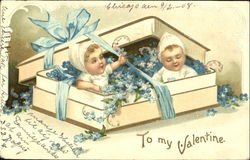 Two infants inside a box filled with flowers Postcard