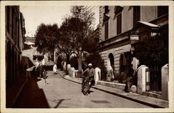 Man Walking his Bike down the Street Postcard