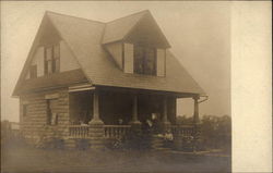 Two-story stone home with woman on front steps Buildings Postcard Postcard