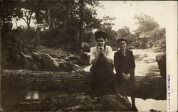 Woman and boy sitting on a log Postcard Postcard