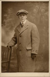 Young man in Overcoat and Cap with hand on chair Men Postcard Postcard