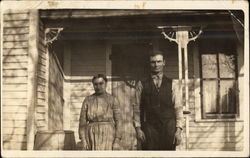 A Couple Pose on Front Porch of Clapboard House Postcard