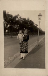 Woman Holding a Baby by a Streetlamp Postcard