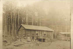 Family outside Log Cabin Postcard