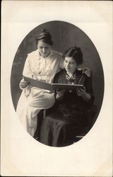 Two Women Peruse an Album Postcard