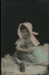 Girl in pink bonnet & blue dress holding cat Postcard