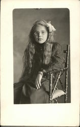 Girl with long hair and glasses sitting on chair Postcard