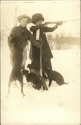 Man and woman with rifles, dogs at feet Postcard