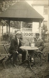 Two men sitting at round table outside Postcard Postcard