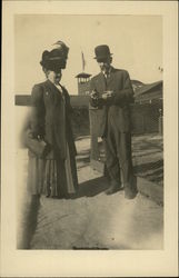 Couple Standing by Wire Fence, Woman with Large Hat Postcard