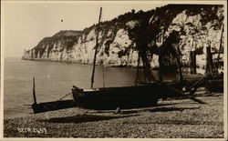 Boats on the Shore with a Rocky Cliff and Water in the Background Postcard