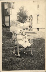 Snapshot of Baby in Chair with Doll Postcard