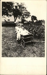 Four small children sit in a wagon in the backyard of a house (Early 1900's) Postcard Postcard Postcard