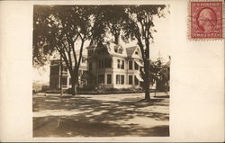 A large house on a tree lined road Postcard