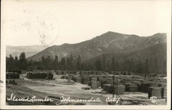 Stacked Lumber with Mountains in the Background Postcard