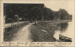 Curved Shoreline Near Trees and Boat in Water Postcard