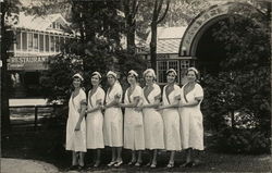 Seven Women in Work Uniforms Posing Outdoors Near Restaurant Postcard