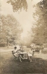 Three Women Seated at Table Outdoors, Man Leaning on Car Postcard