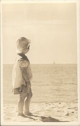 Child on Beach Regarding Sailboat in the Distance Postcard