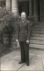 Man in Suit Holding Hat Standing in Front of Steps Postcard