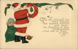 Santa Hanging a Wreath with his Toy Bag Postcard