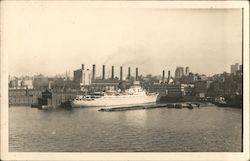 Steamer docked in front of smokestacks and city skyline Postcard