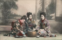 Three Japanese geishas seated around a bowl Postcard