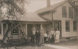 Family Standing in Front of 2-Story House Postcard