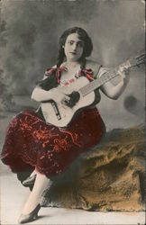 A Woman Sitting on a Rock Playing a Guitar Postcard