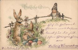 Troll leaning over a fence watching rabbits hiding colored eggs. With Bunnies Postcard Postcard Postcard