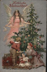 An angel overlooking children around a Christmas tree Postcard