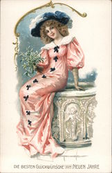 A woman smiling and dressed in a long pink dress with a blue hat. Postcard