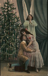 A Man and Woman Hugging in Front of a Christmas Tree and an Angel Postcard