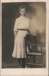 Studio portrait of young woman standing at chair Postcard