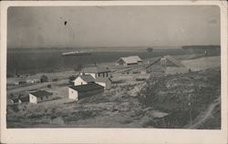 View of village with train in the distance. Postcard