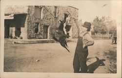 Man in overalls and his dog jumping up to grab food Postcard