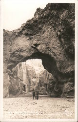 Couple standing below a natural stone arch Death Valley, CA Postcard Postcard Postcard