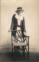 A Woman in a Hat Leaning on Arts & Crafts Style Chair Postcard